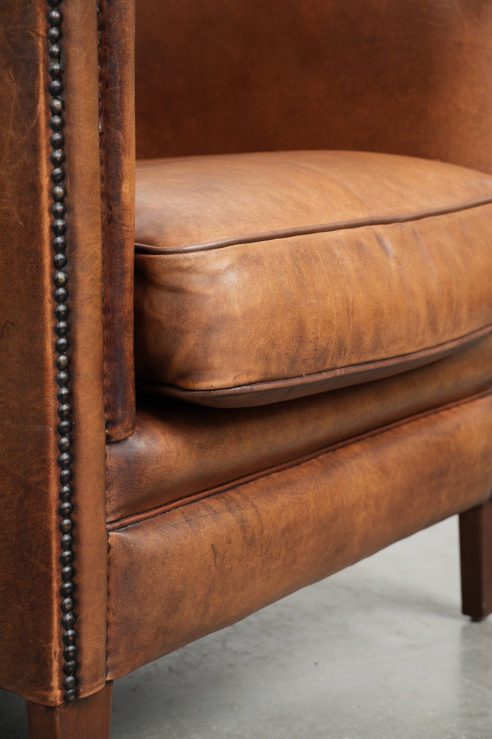 Sheepskin club armchair with a cognac colour finished with decorative nails