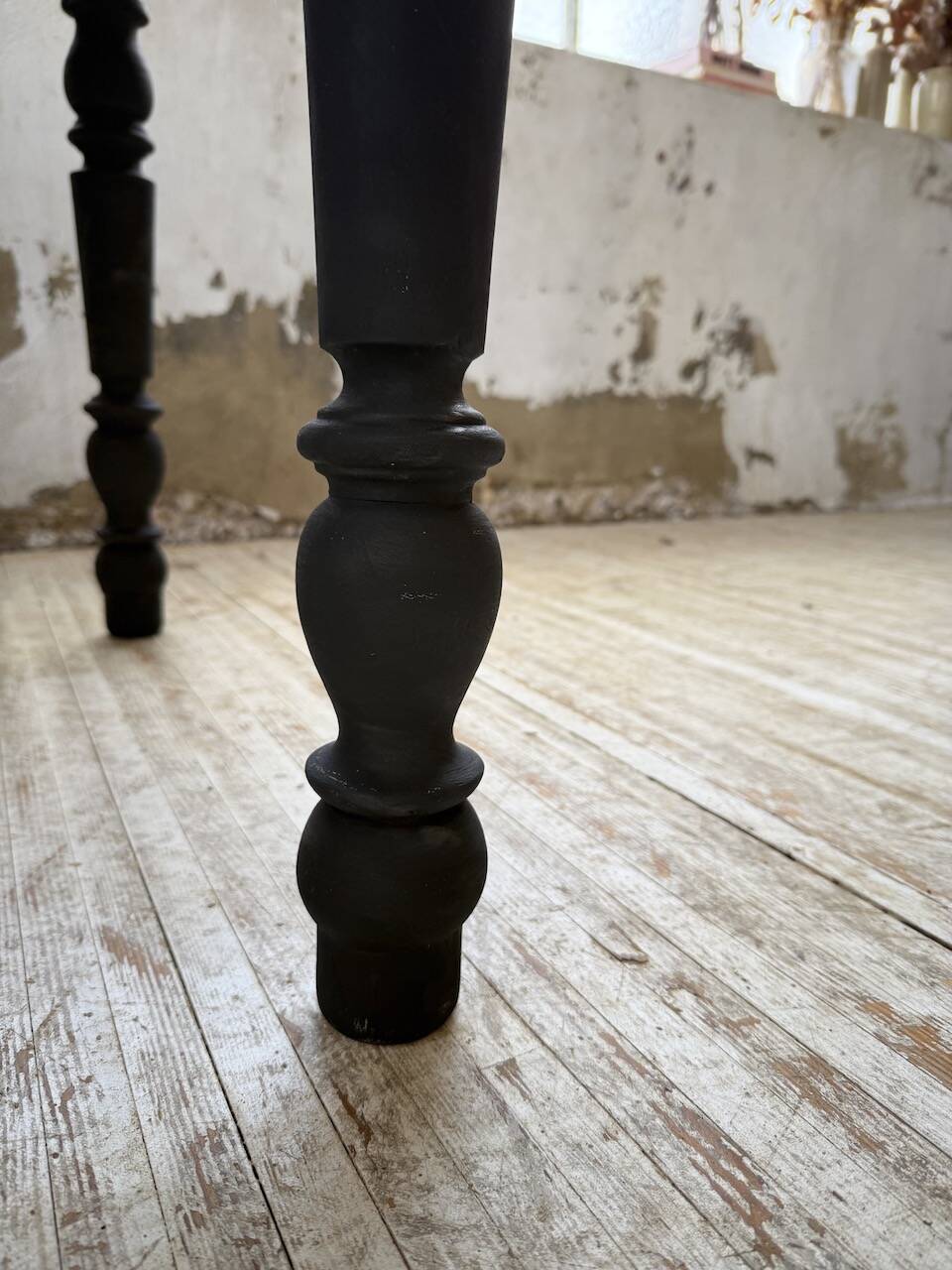 Oak farmhouse table with turned black legs.