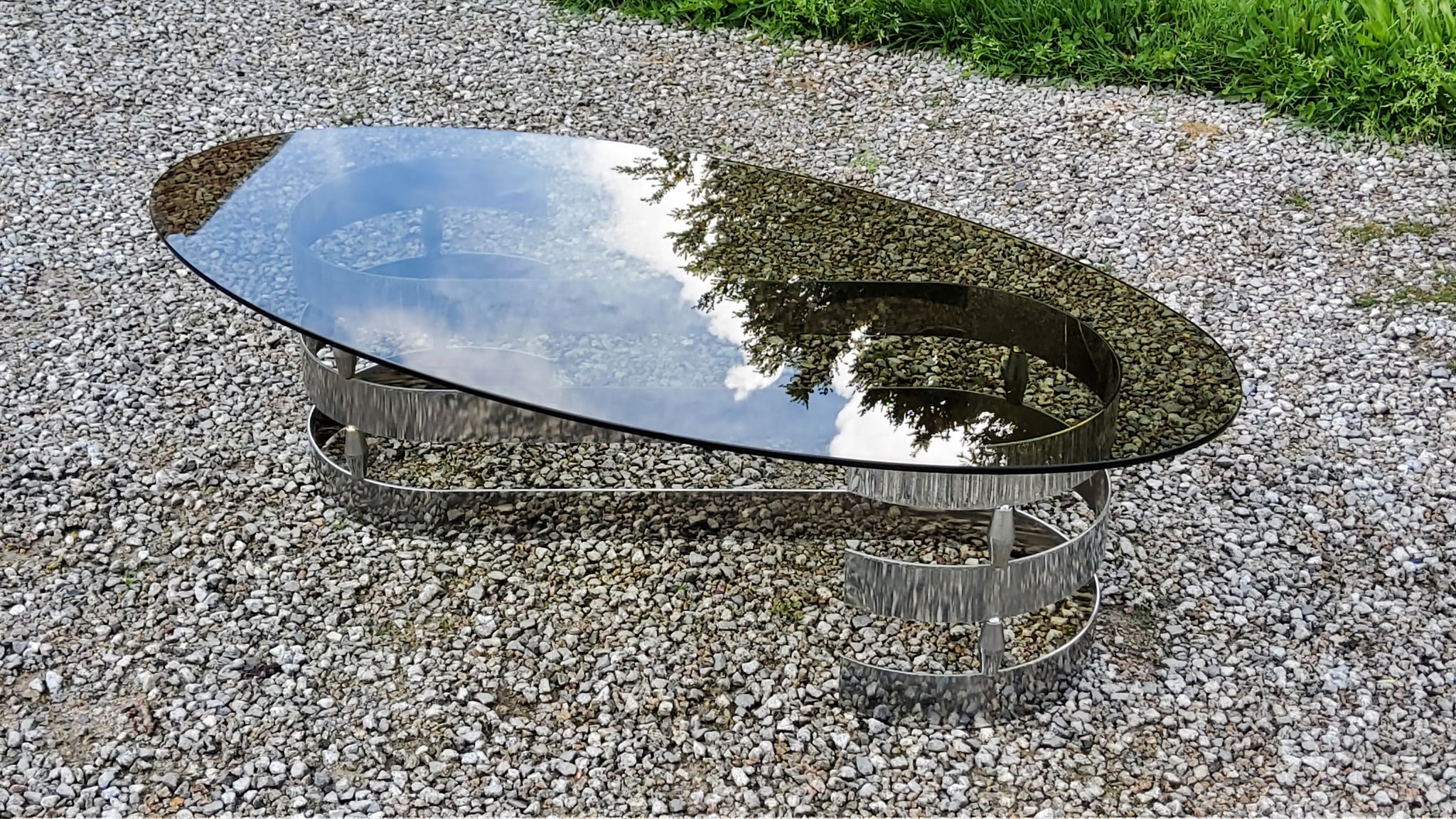 Oval coffee table of the 70s chromed metal base in s smoked glass top