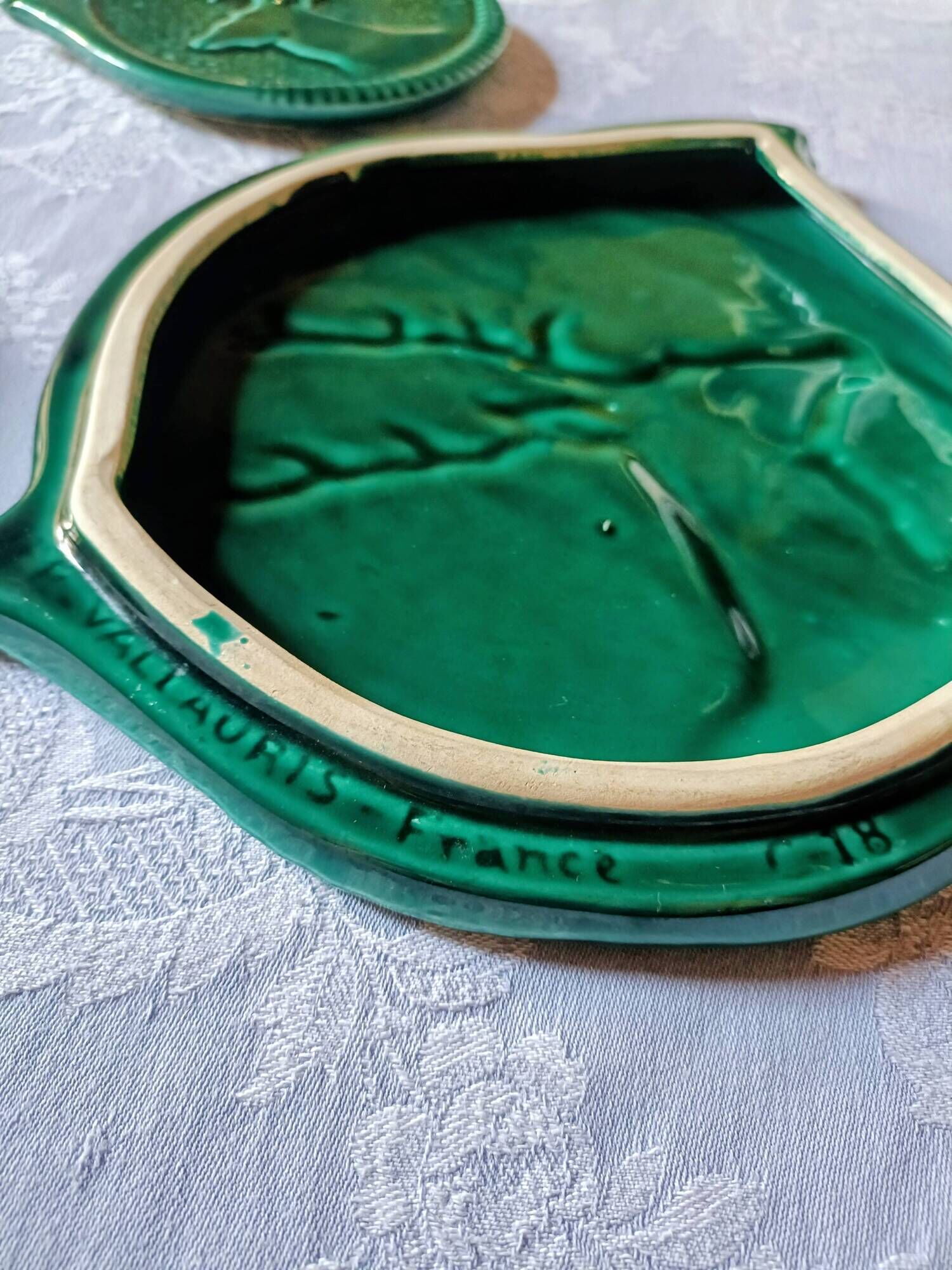 A trivet and two bottle holders in green Vallauris majolica.