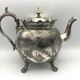 Old teapot pourer in silver metal decorated with foliage and butterflies