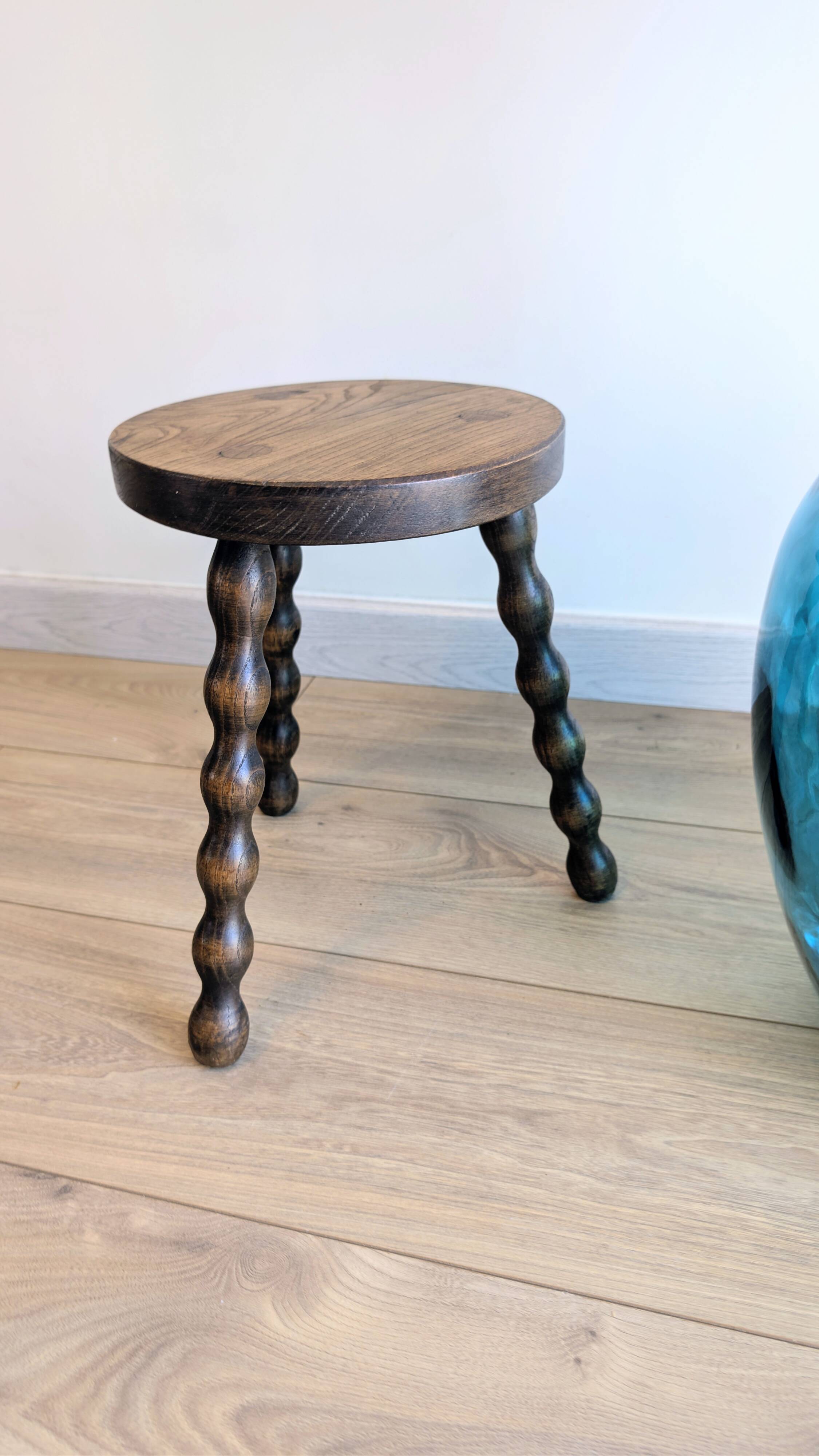 Small wooden tripod stool with turned legs, country style.