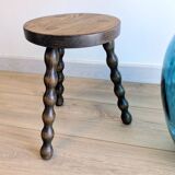 Small wooden tripod stool with turned legs, country style.