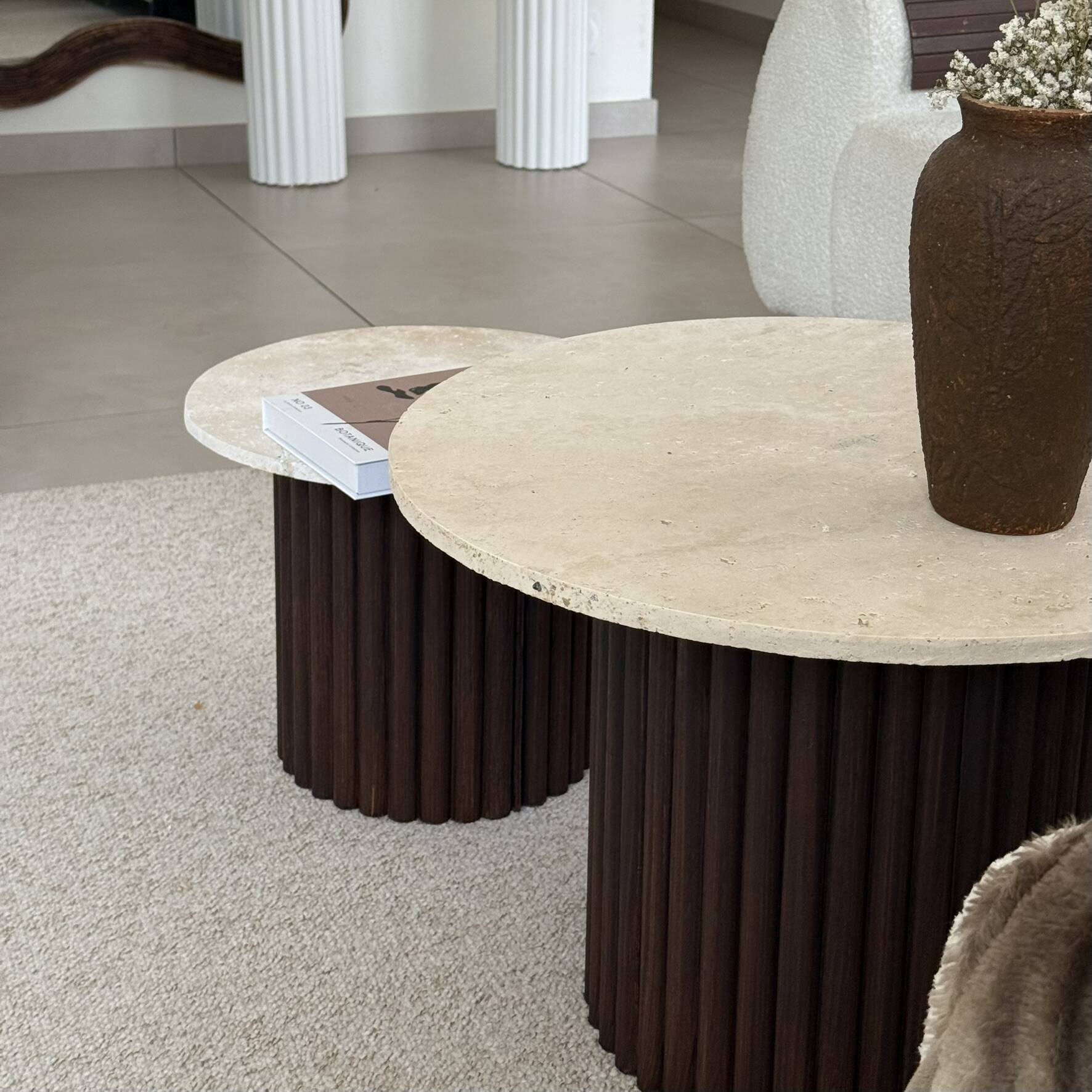 Round nesting coffee table in travertine and dark fluted wood.