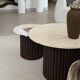 Round nesting coffee table in travertine and dark fluted wood.