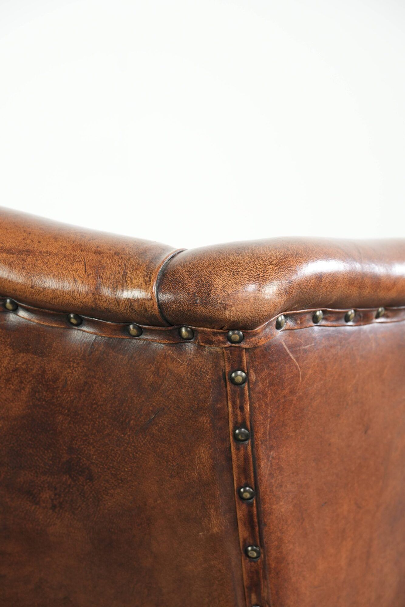 Sheepskin wingback armchair in a warm cognac colour with refined nailhead trim