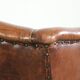 Sheepskin wingback armchair in a warm cognac colour with refined nailhead trim