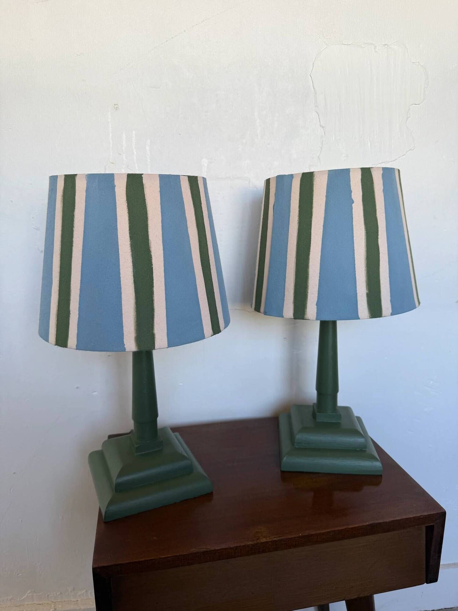 Pair of vintage wooden lamps with their striped beige, blue, and green shades.