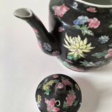 Vintage Chinese teapot with floral polychrome decoration on a black background.