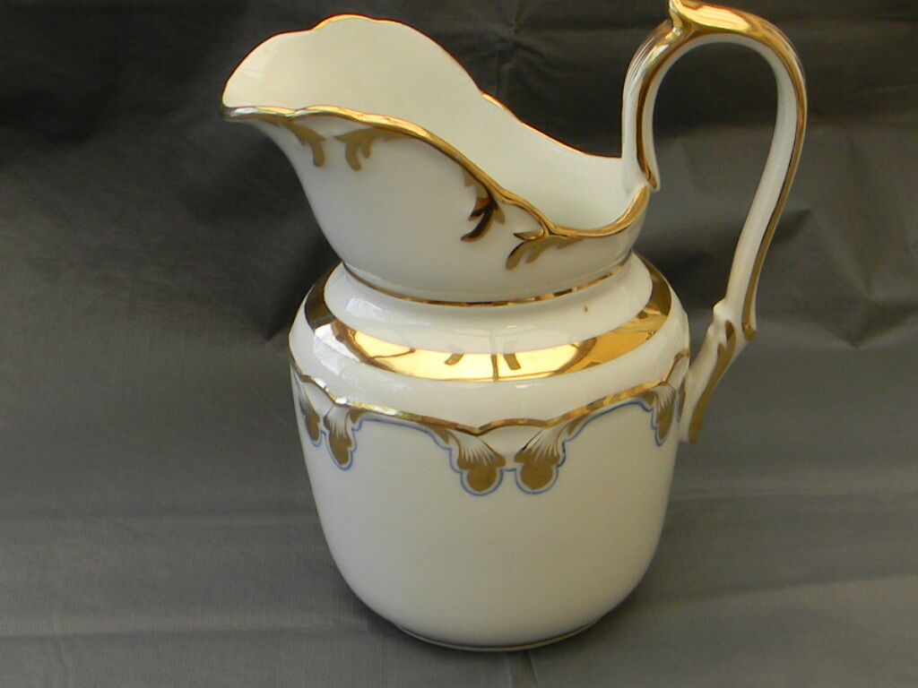 Milk jug or antique pitcher in white and gold porcelain.