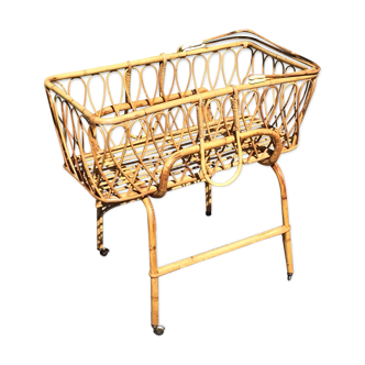 Vintage rattan cradle resting on roller structure 70's