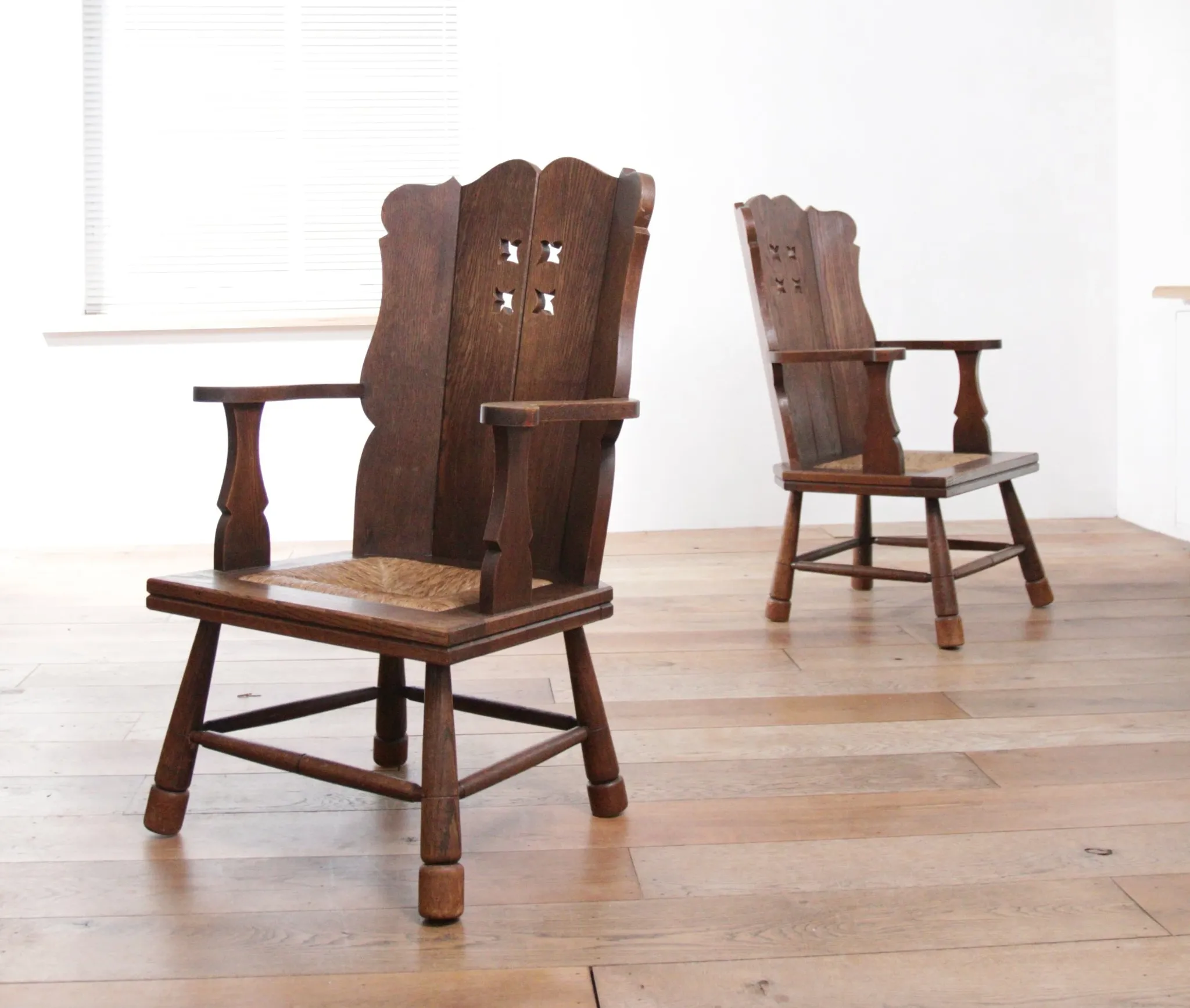 Pair of brutalist oak lounge chairs with rush seats, circa 1935