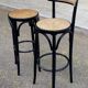 High bistro bar stool in curved black wood with a cane backrest.