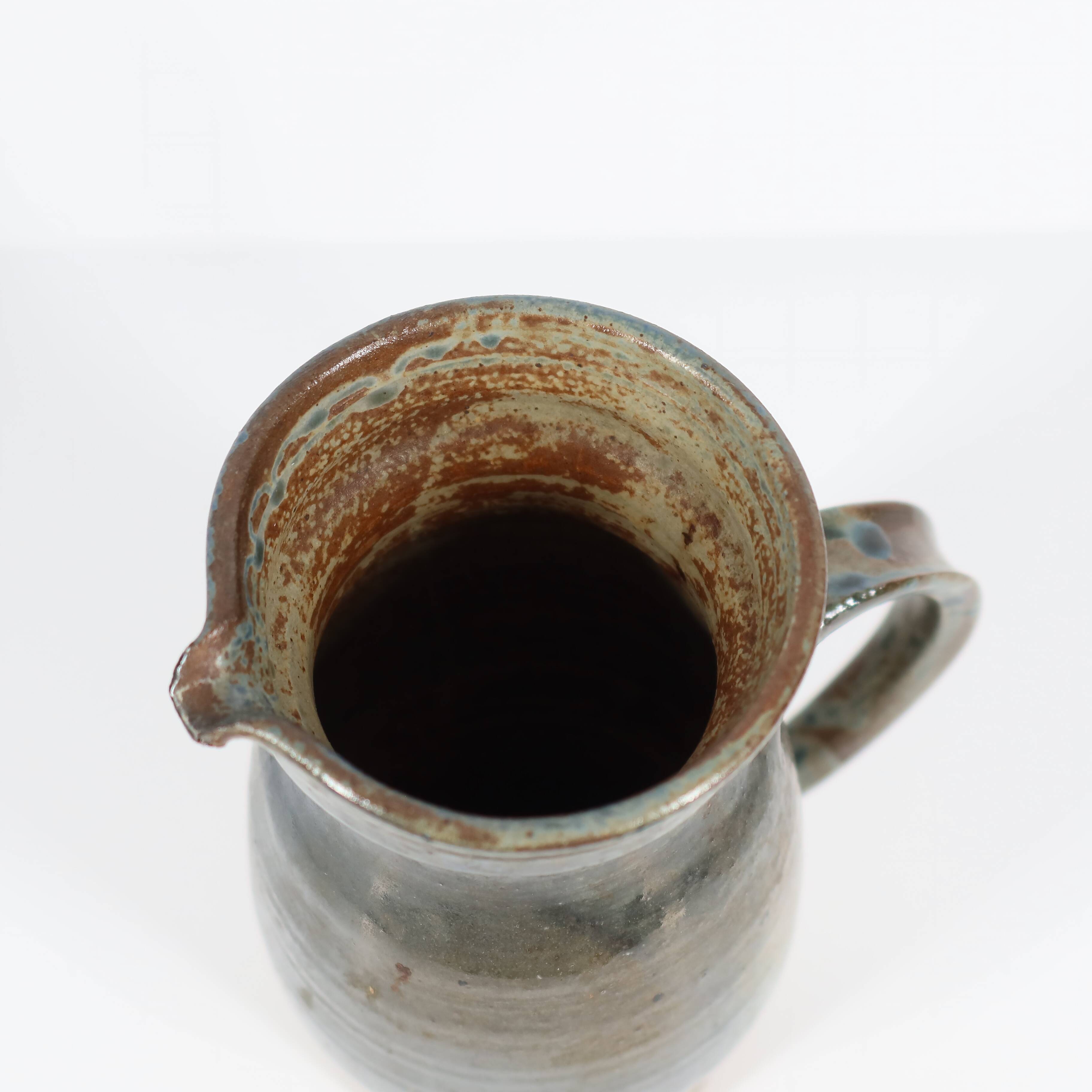 Handcrafted stoneware pitcher with blue-green hues, signed piece