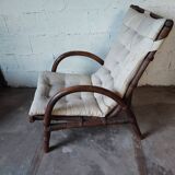 Relaxed armchair in bamboo and rattan with its small side table. Beige linen cushion.