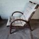Relaxed armchair in bamboo and rattan with its small side table. Beige linen cushion.