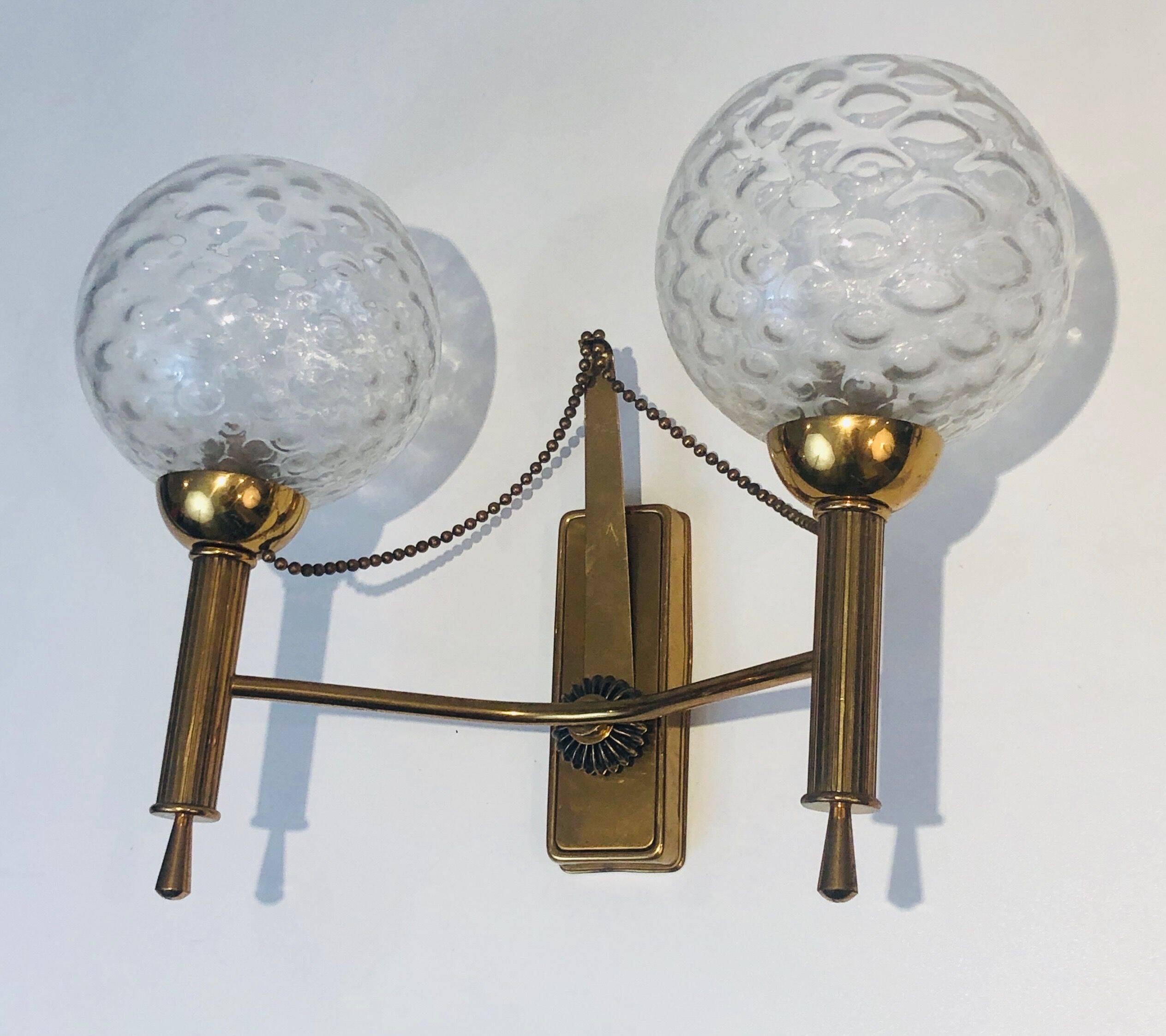 Pair of brass wall lights with glass globes. Around 1970.