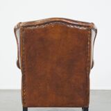 Sheepskin leather wingback chair with a red corduroy seat cushion