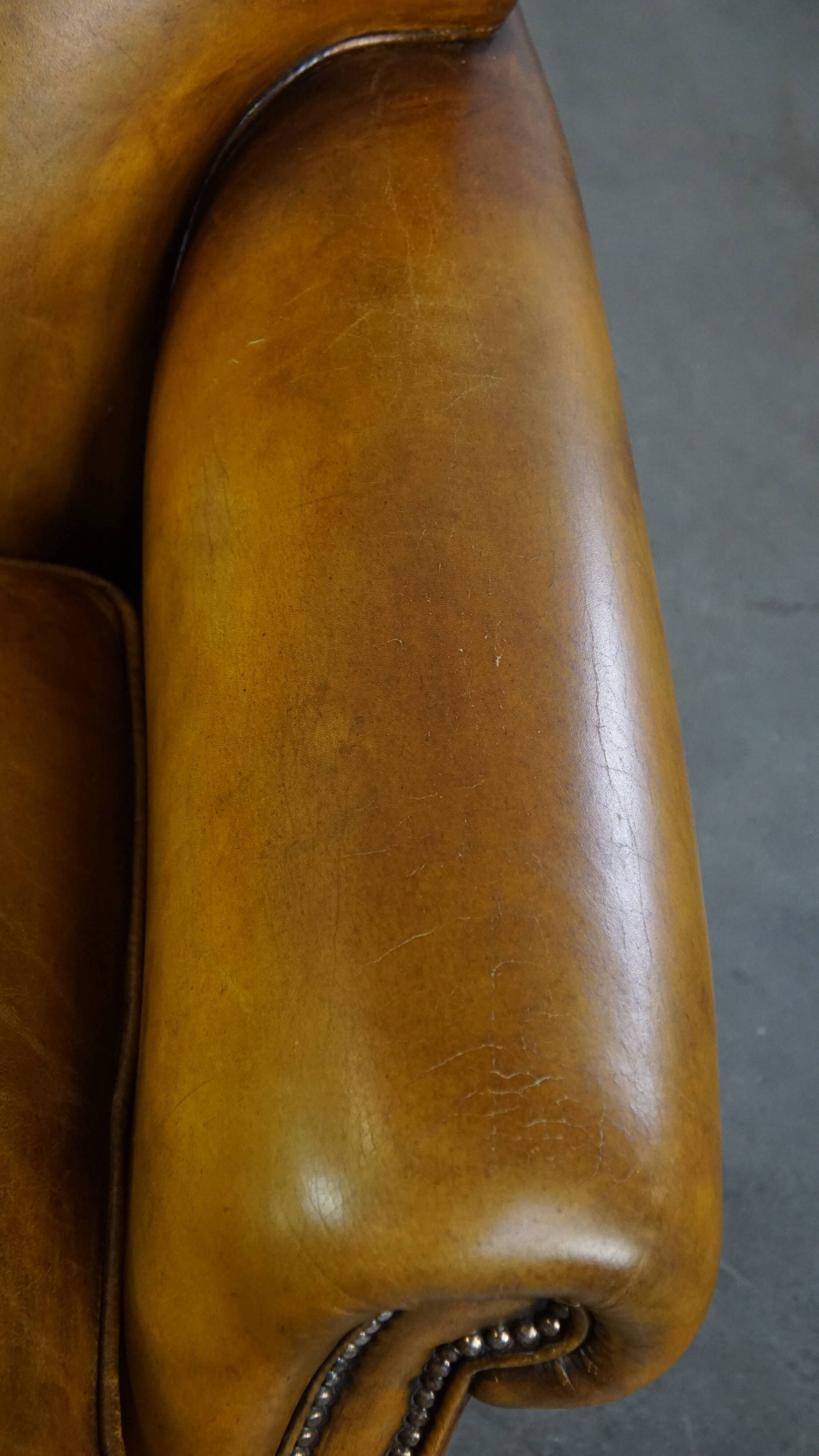 Comfortable large yellow English-style leather armchair with a fine finish and decorative nails