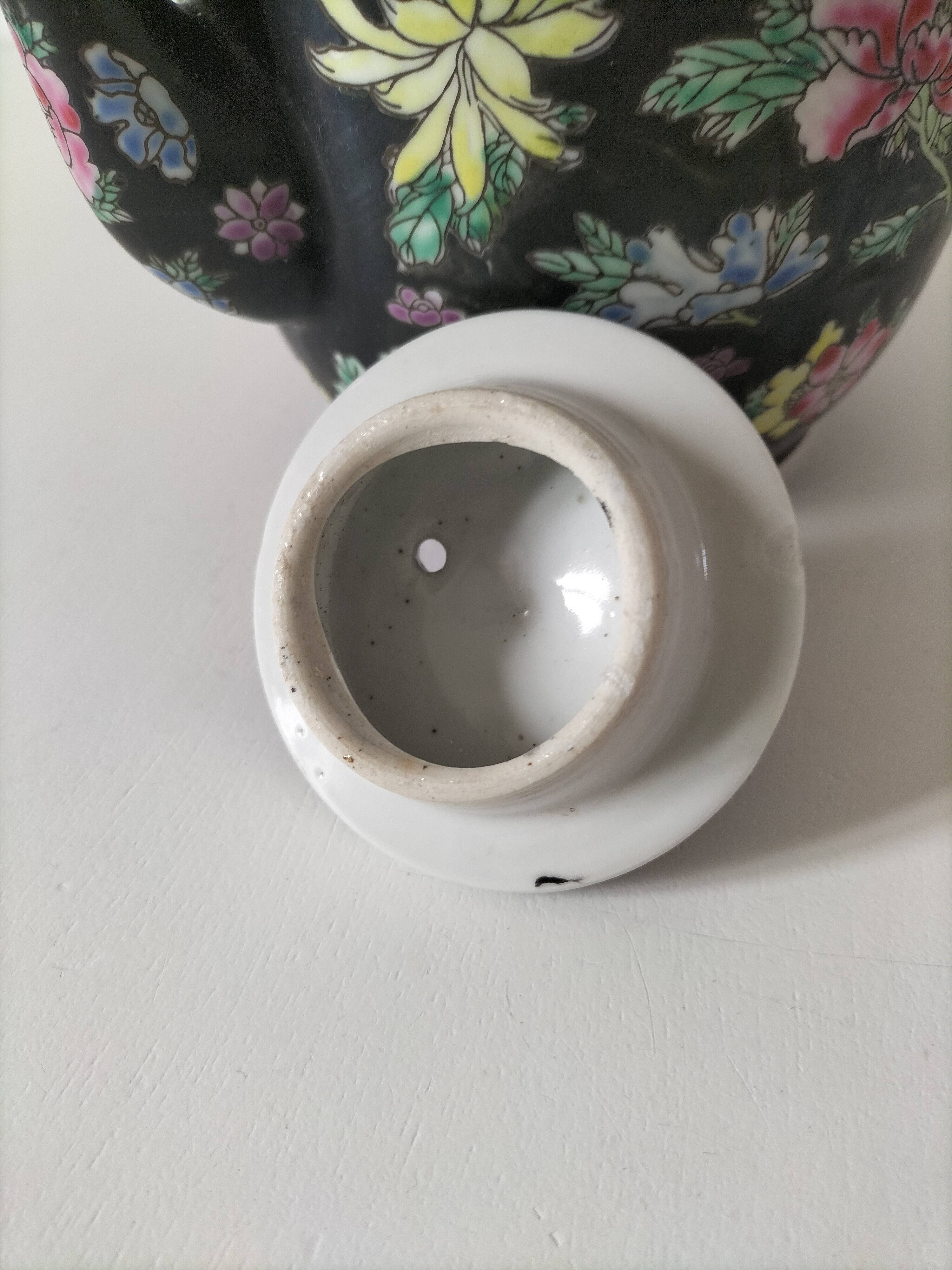 Vintage Chinese teapot with floral polychrome decoration on a black background.
