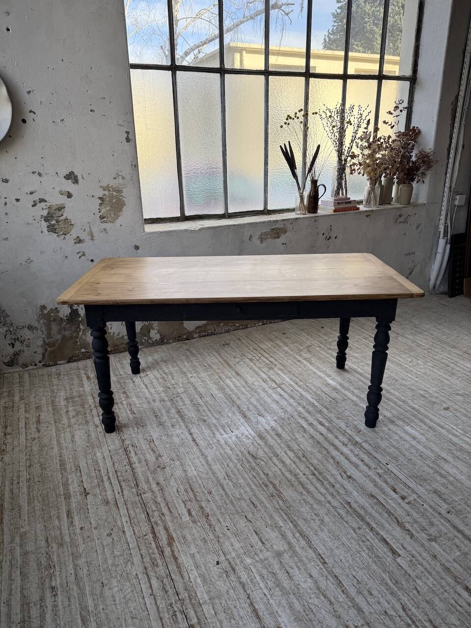 Oak farmhouse table with turned black legs.
