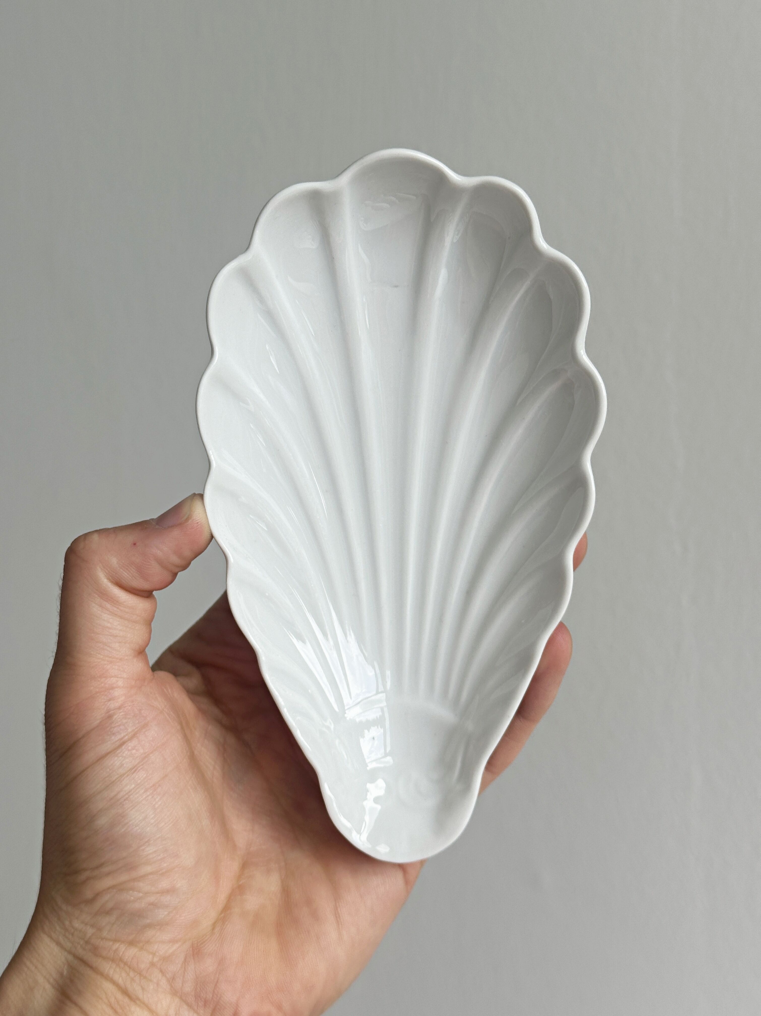 Set of white porcelain ramekins, ribbed shell shape.