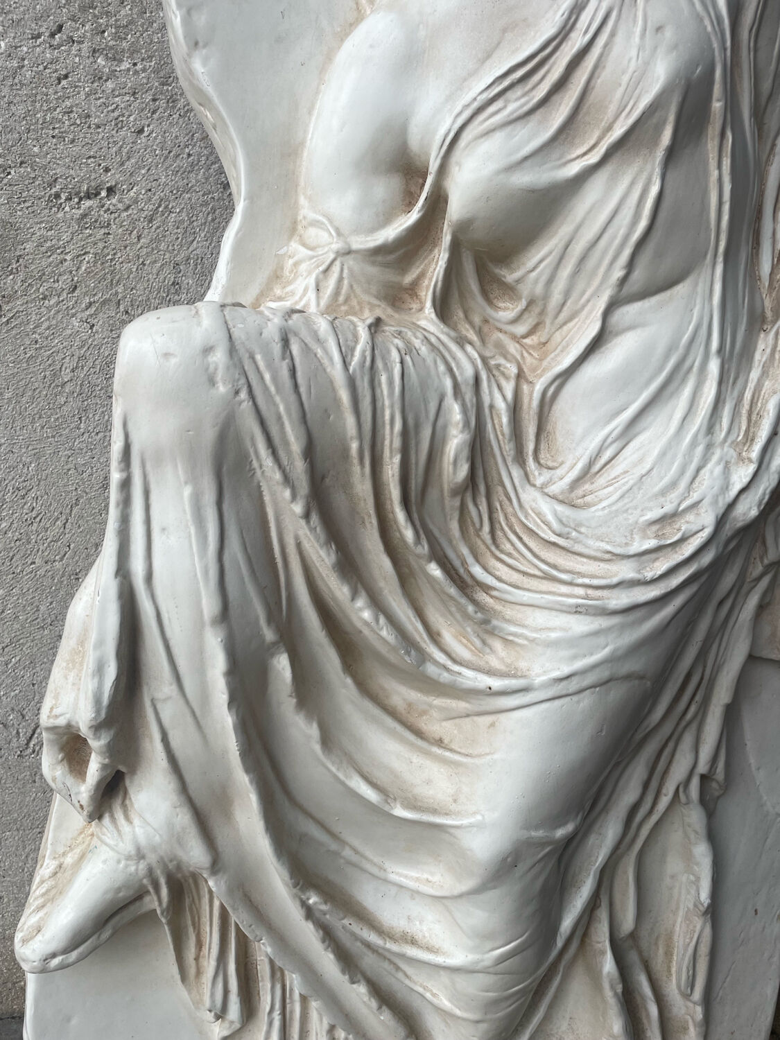 Ancient plaster bas-relief of Nike fastening her sandal.