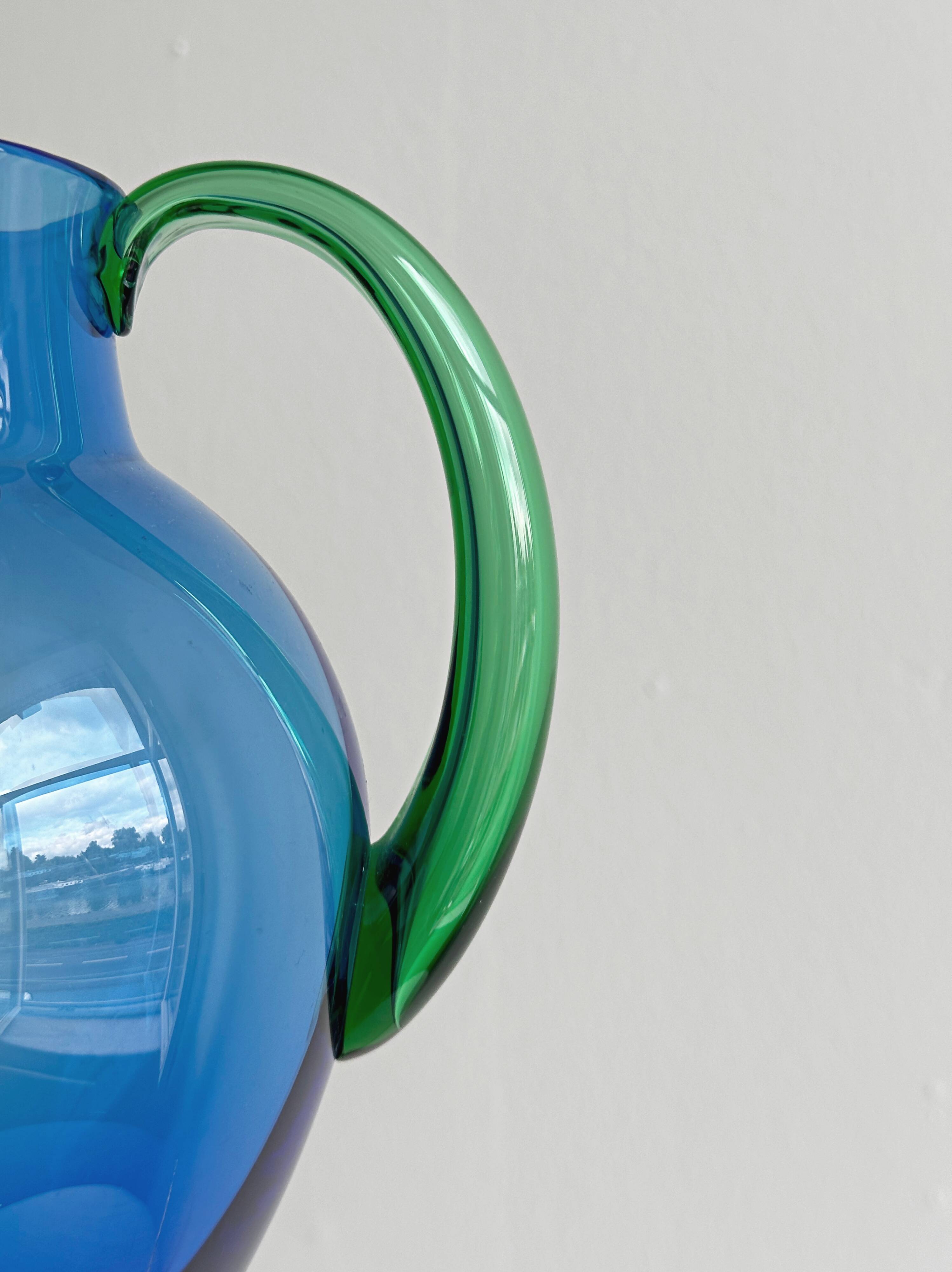Translucent blue glass jug with a green handle.