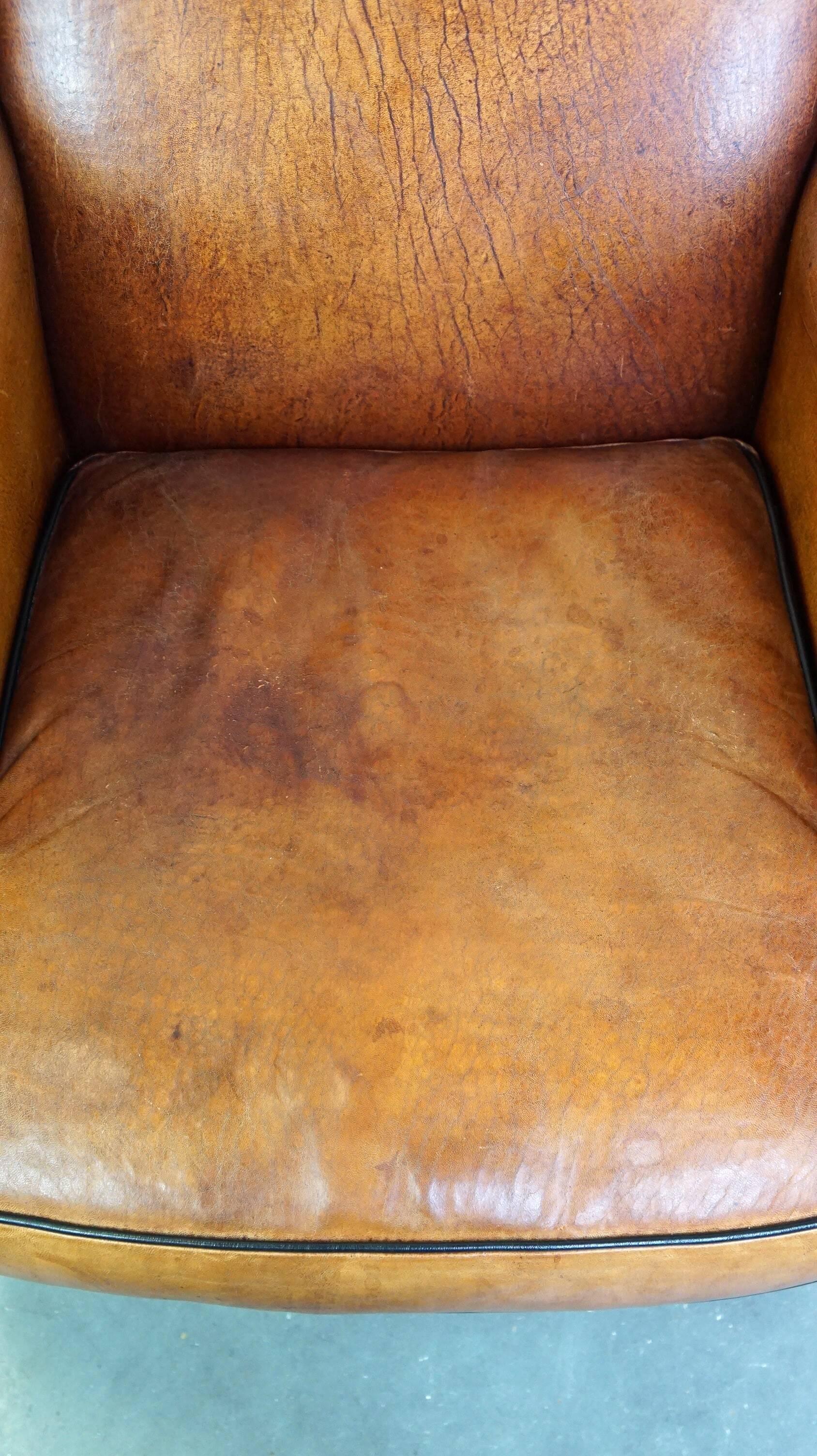 Subtle and well-maintained sheep leather armchair on brass front wheels