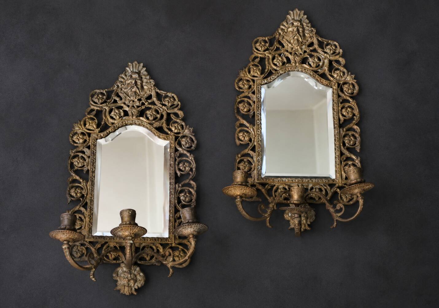 Pair of mirror wall sconces with brass candle holders.