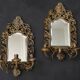 Pair of mirror wall sconces with brass candle holders.