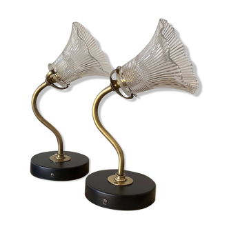 Pair of brass swan neck wall lights with transparent glass shades.