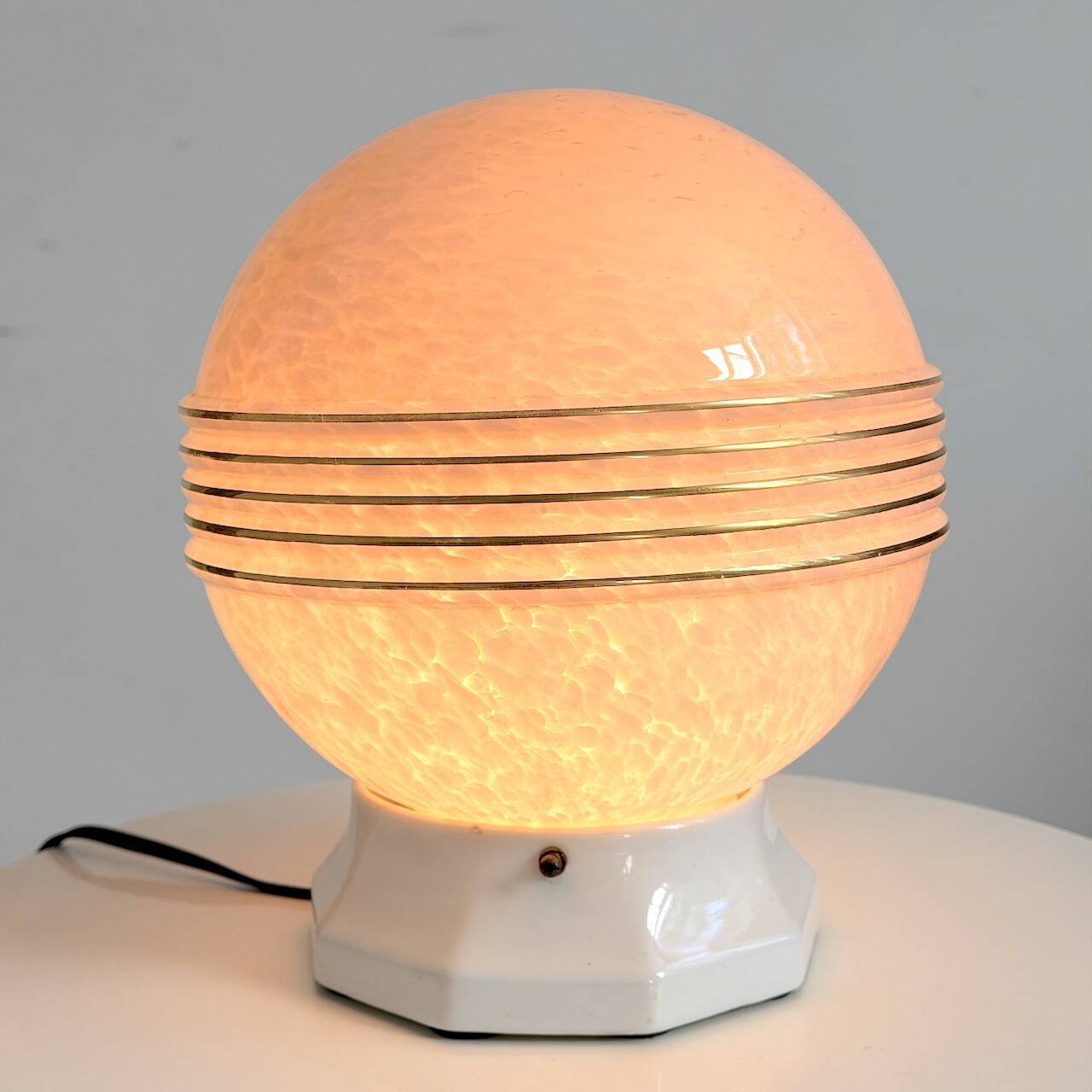 Art Deco lamp with a speckled pink glass globe and a white ceramic base.