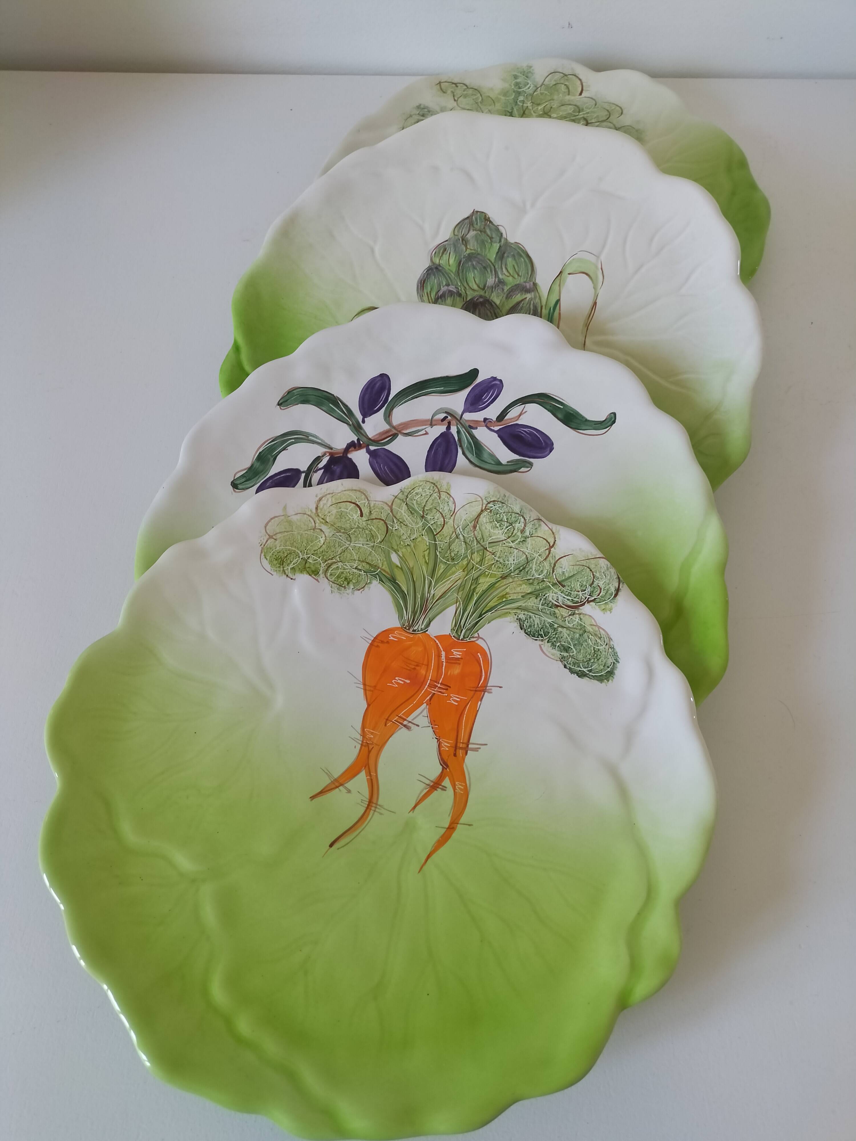 4 hand-decorated earthenware plates with vegetable and green leaf designs.