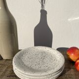 4 black speckled dessert plates on a vintage white background