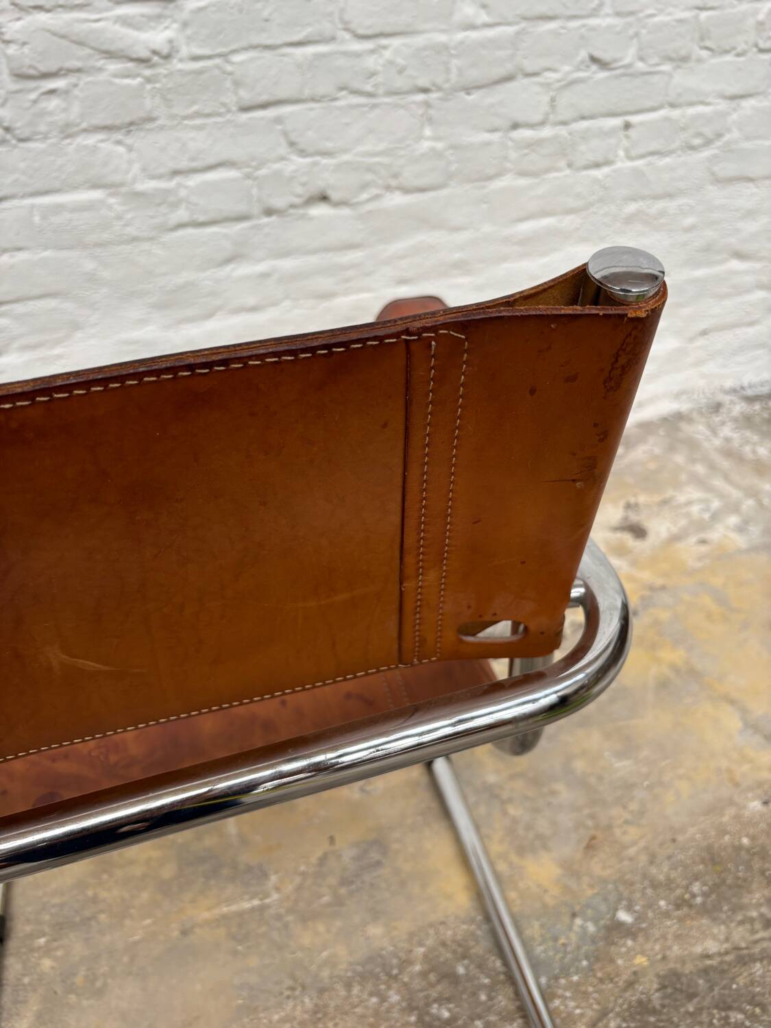 Vintage aluminum tube and tan leather armchair