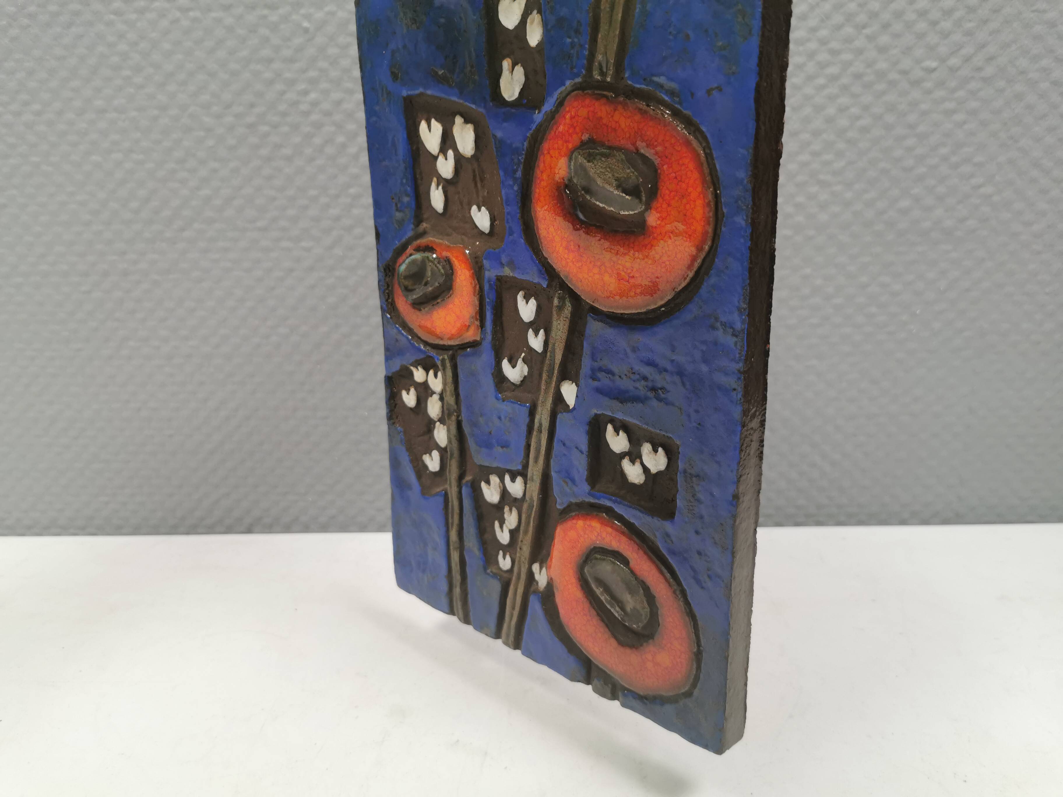 Ceramic relief in attractive blue with a motif of white/red flowers.