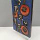 Ceramic relief in attractive blue with a motif of white/red flowers.
