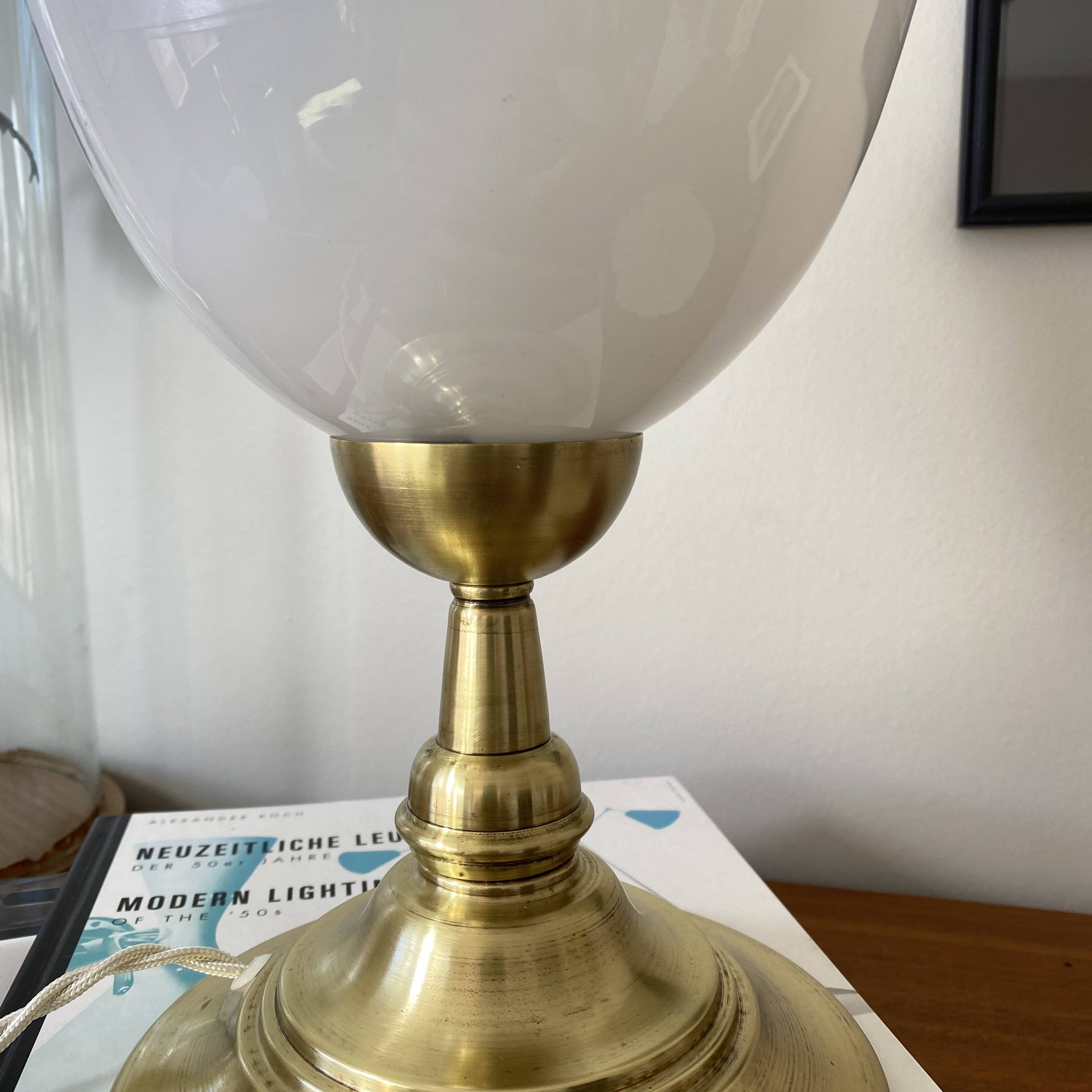 Antique white opaline glass globe table lamp with a brass base.
