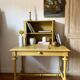 Desk table from the late 19th century, painted mustard, with turned stretcher.