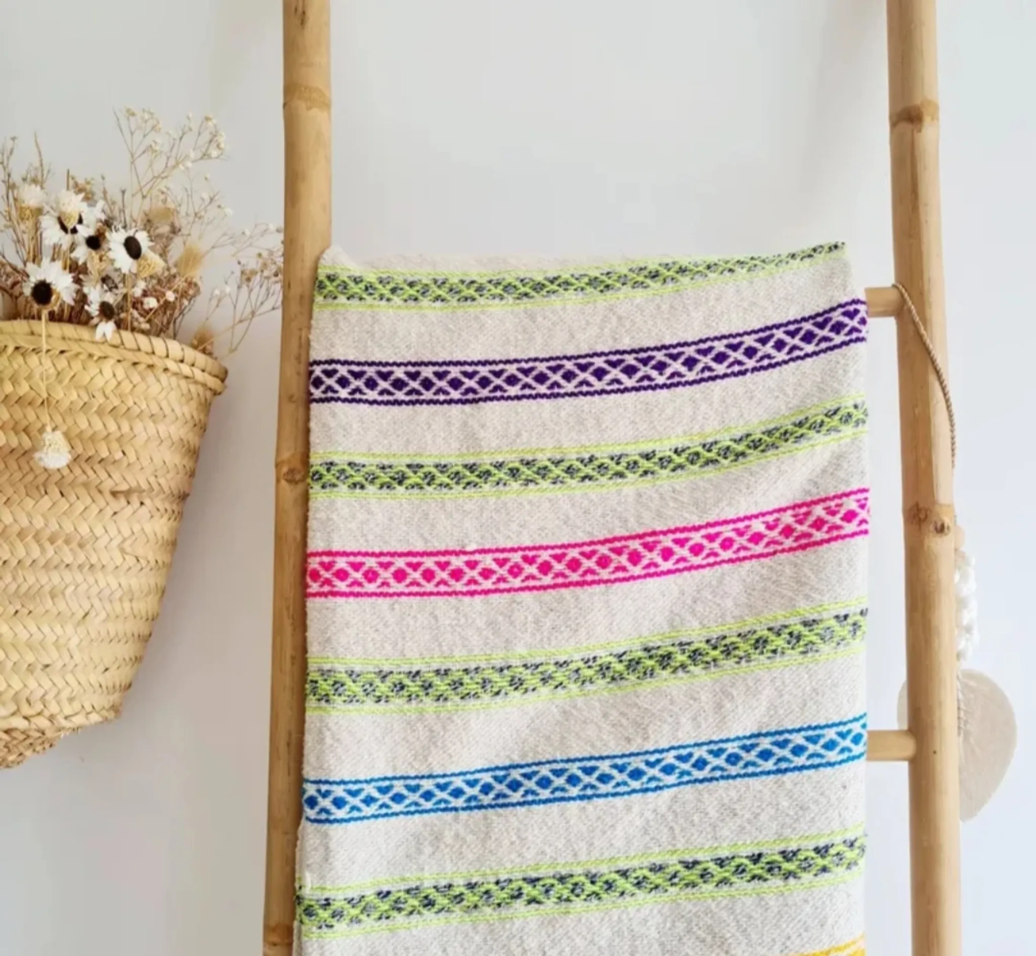 Moroccan plaid made of handwoven wool, decorated with stripes and pom-poms.