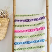 Moroccan plaid made of handwoven wool, decorated with stripes and pom-poms.