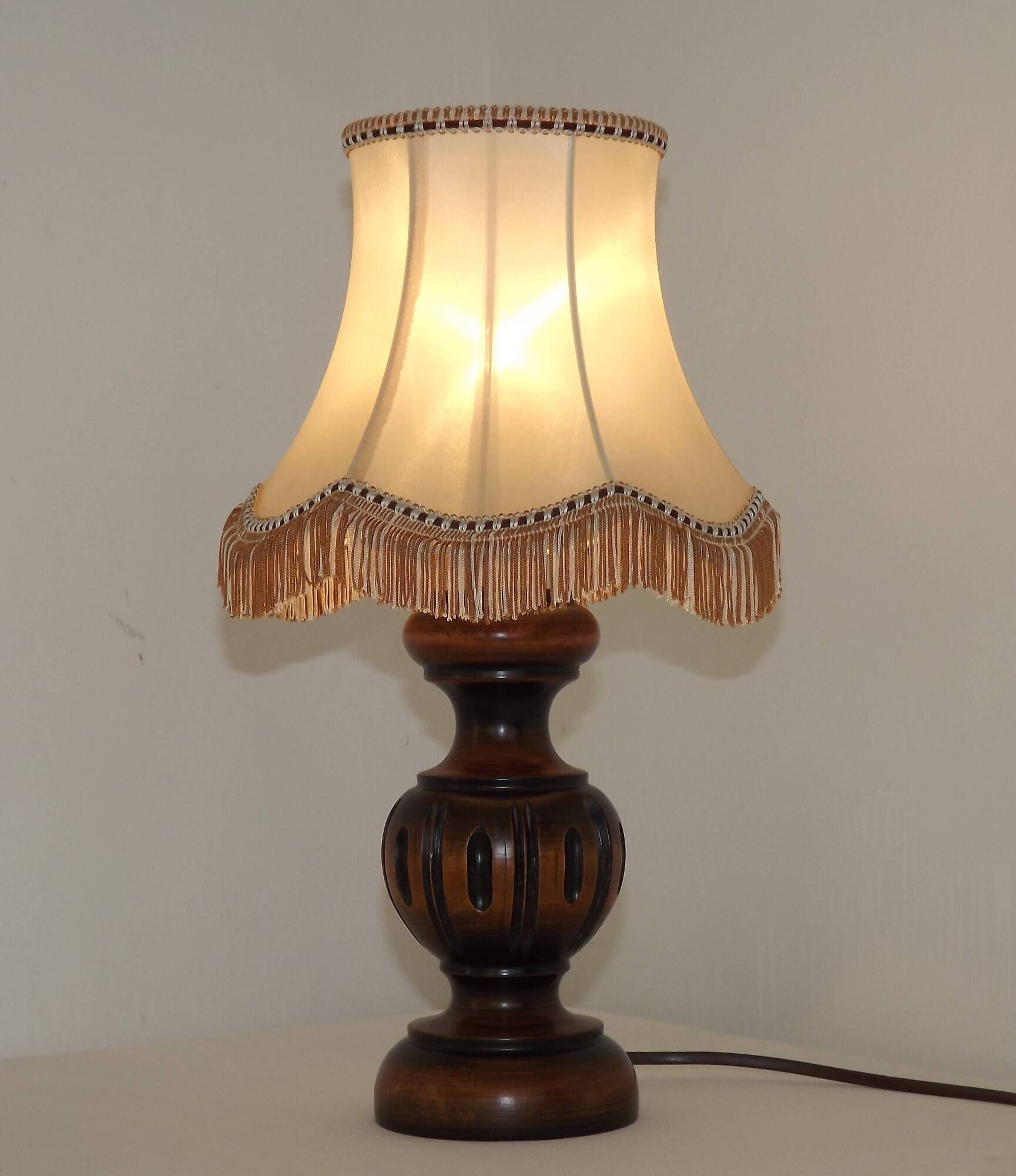 Mid-century French table lamp made of turned carved wood with a fringed shade.
