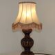 Mid-century French table lamp made of turned carved wood with a fringed shade.