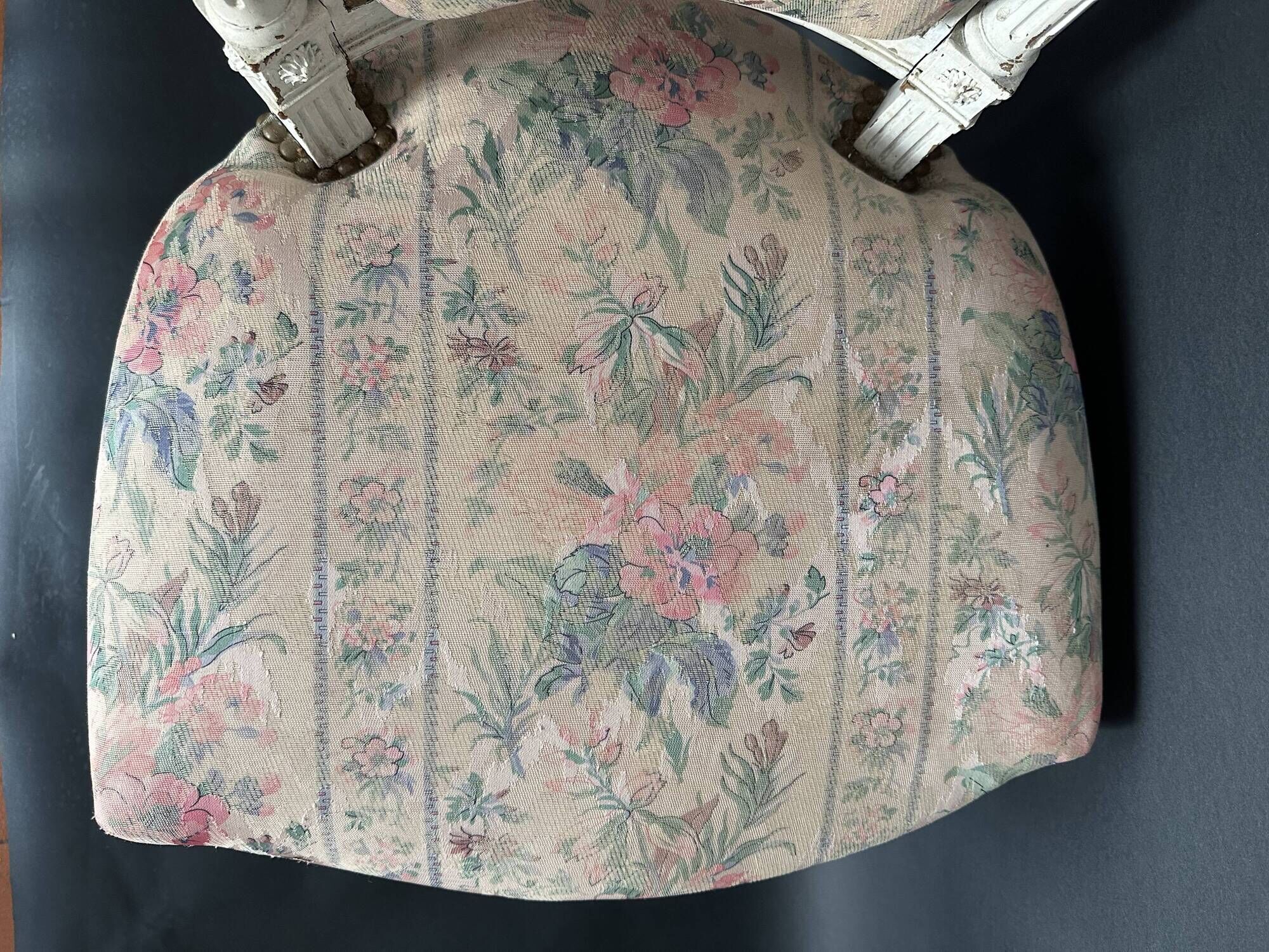 Antique Louis XVI style chair with patinated wood and floral fabric.