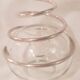 Round glass candle holder with silver-plated metal spiral.