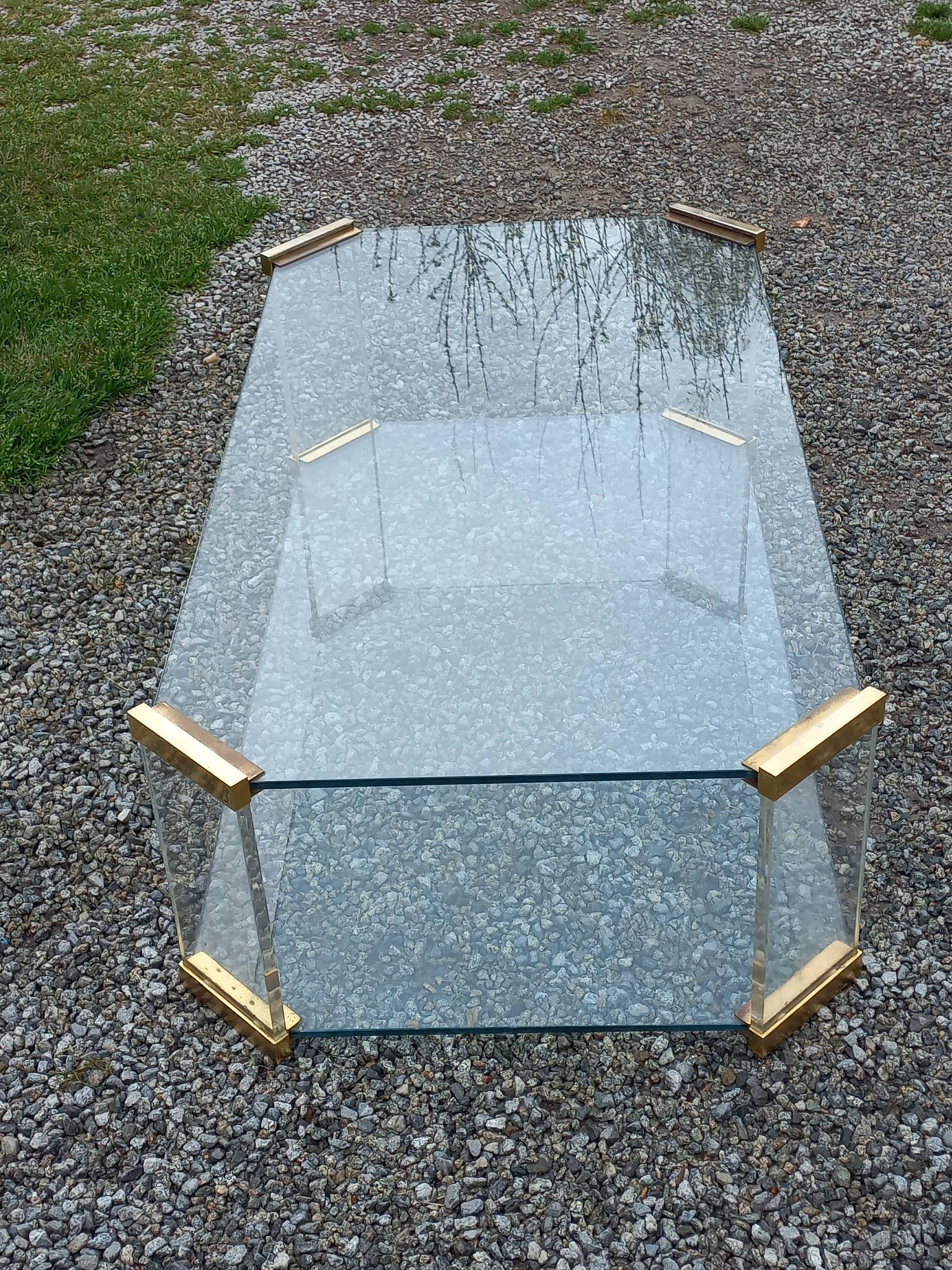1970s designer coffee table in glass, plexiglass, and gold metal.