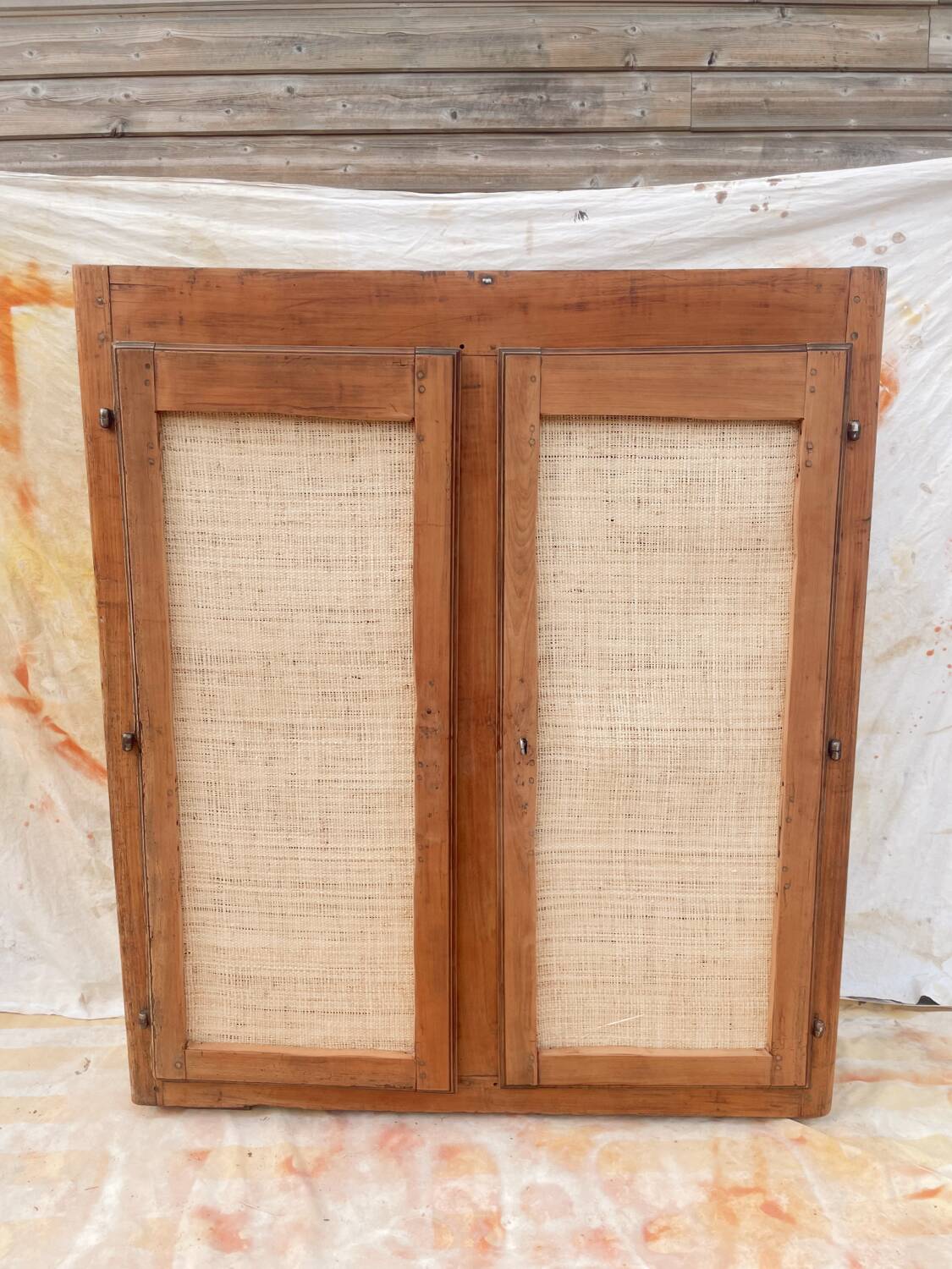 Low cabinet in raw wood and woven raffia.