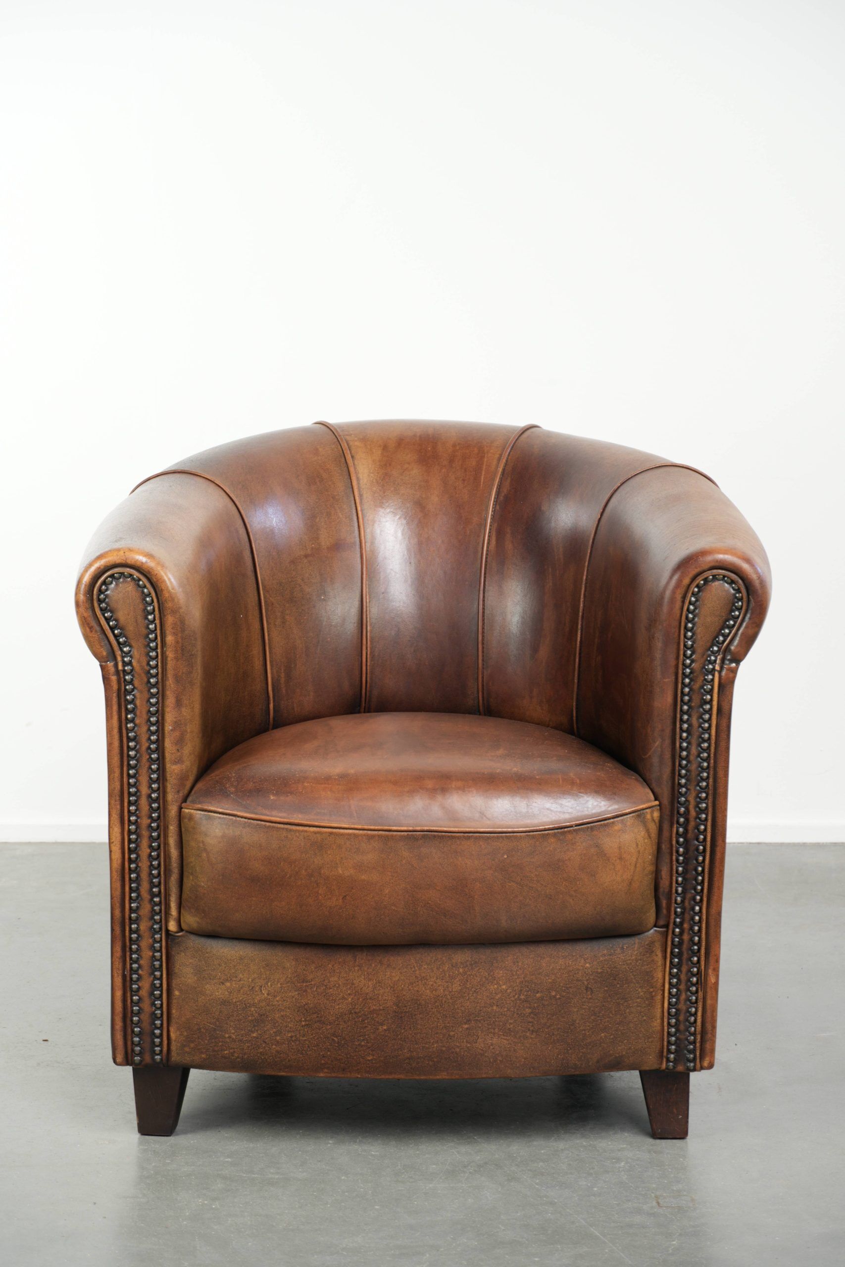 Sheepskin clubarmchair with beautiful patina finished with decorative nails