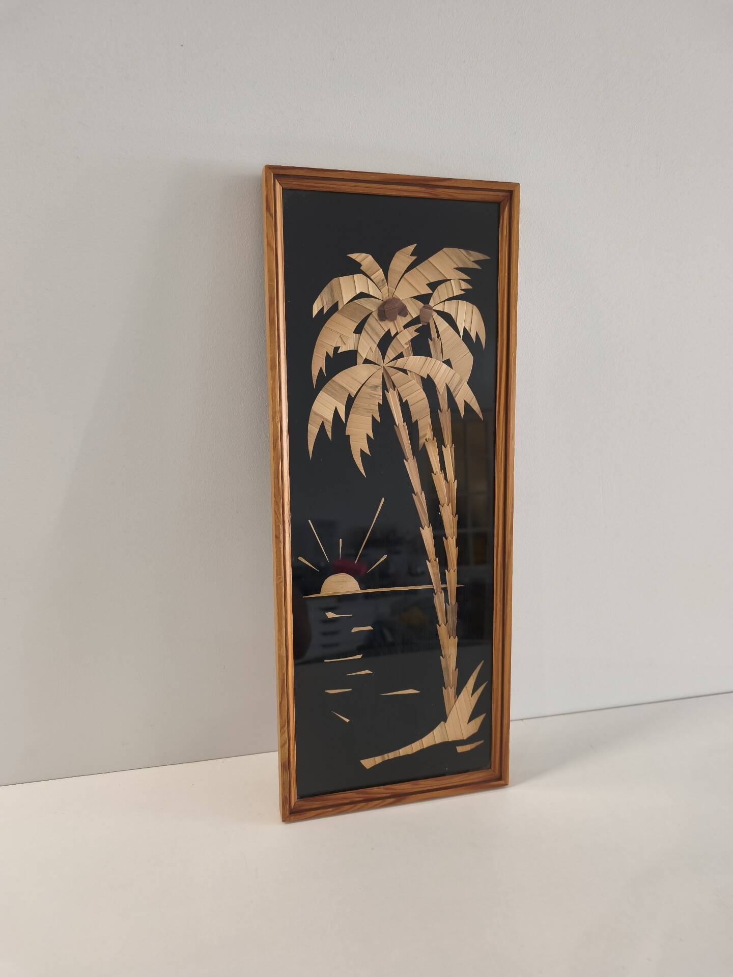 Vintage frame with palm tree and sun in wood or wicker.
